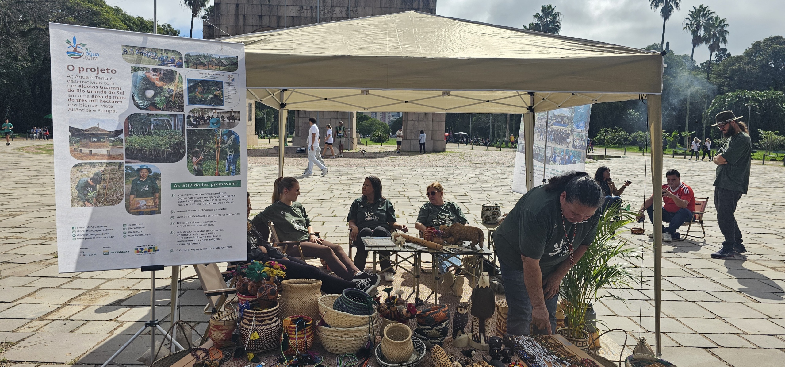 Espaço montado pelo Projeto Ar, Água e Terra no Brique da Redenção reuniu exposição de artesanato Guarani e conversas com o público, criando um ponto de encontro entre saberes tradicionais e a dinâmica urbana.